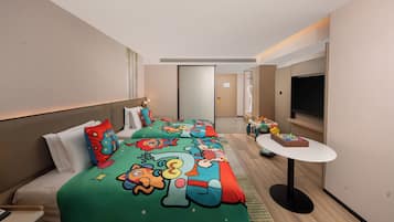 A hotel room with a large bed, a small table, a TV, and a door leading to another room.