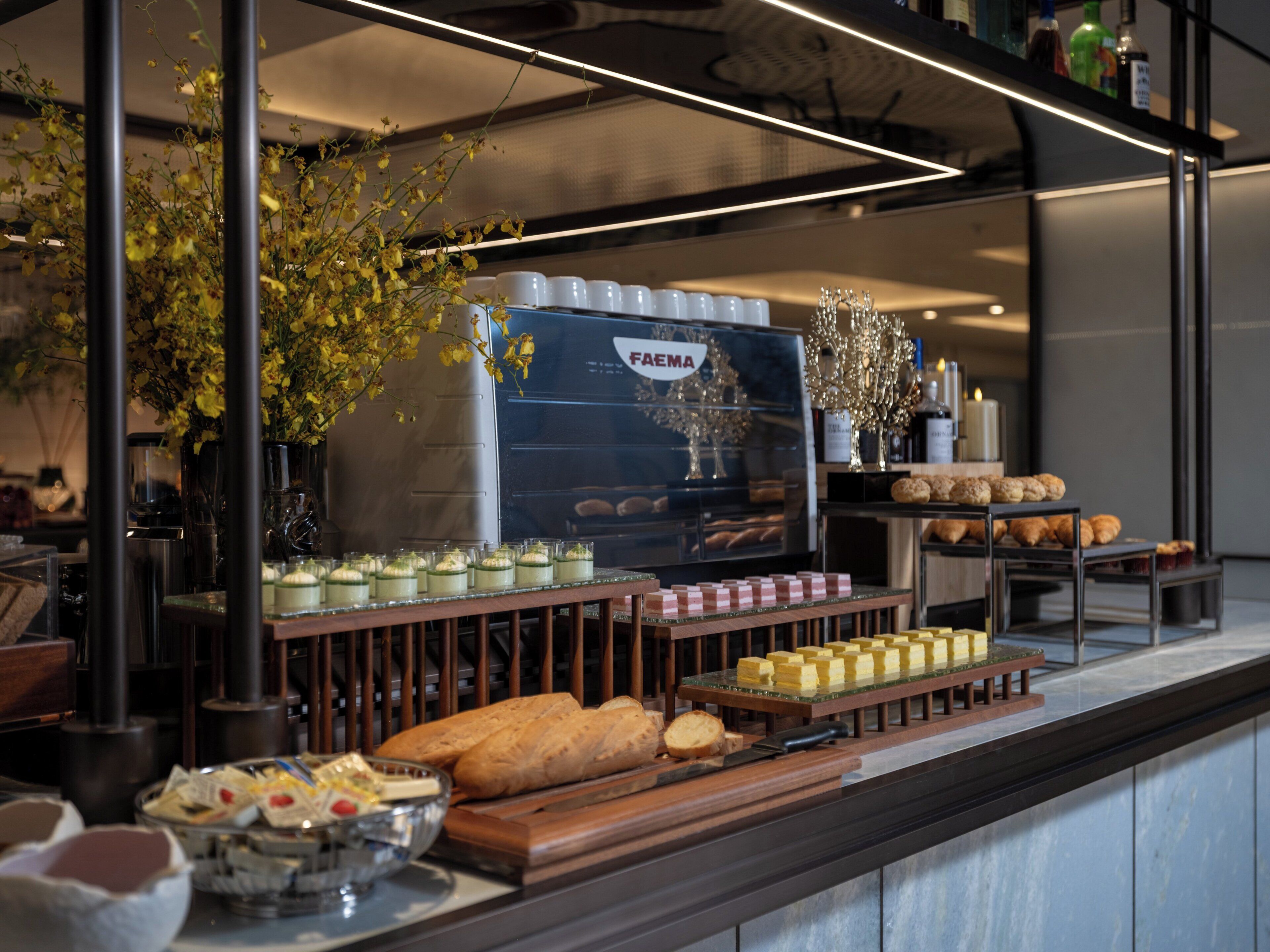 A buffet with various food items, including bread, pastries, and a selection of cheeses.