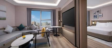 A modern hotel room with a sofa, a small table, a TV, and a bed.