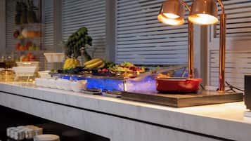 Disposição de buffet com diversos alimentos e uma panela vermelha em uma bancada de mármore.