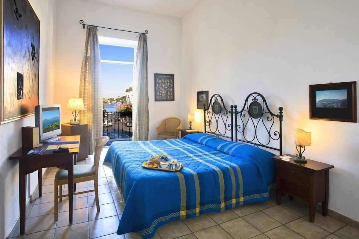 Ein Schlafzimmer mit Bett, Schreibtisch, Stuhl und einem Fenster mit Vorhängen.