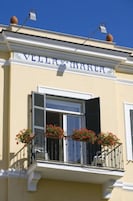 A building with a balcony, a window with shutters, and a sign above the window.