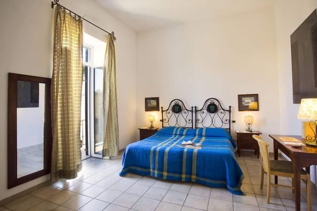 Ein Schlafzimmer mit Bett, Vorhängen, Schreibtisch und zwei Nachttischlampen.