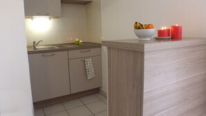 Una cocina con encimera de madera, un cuenco de fruta y dos velas encendidas.