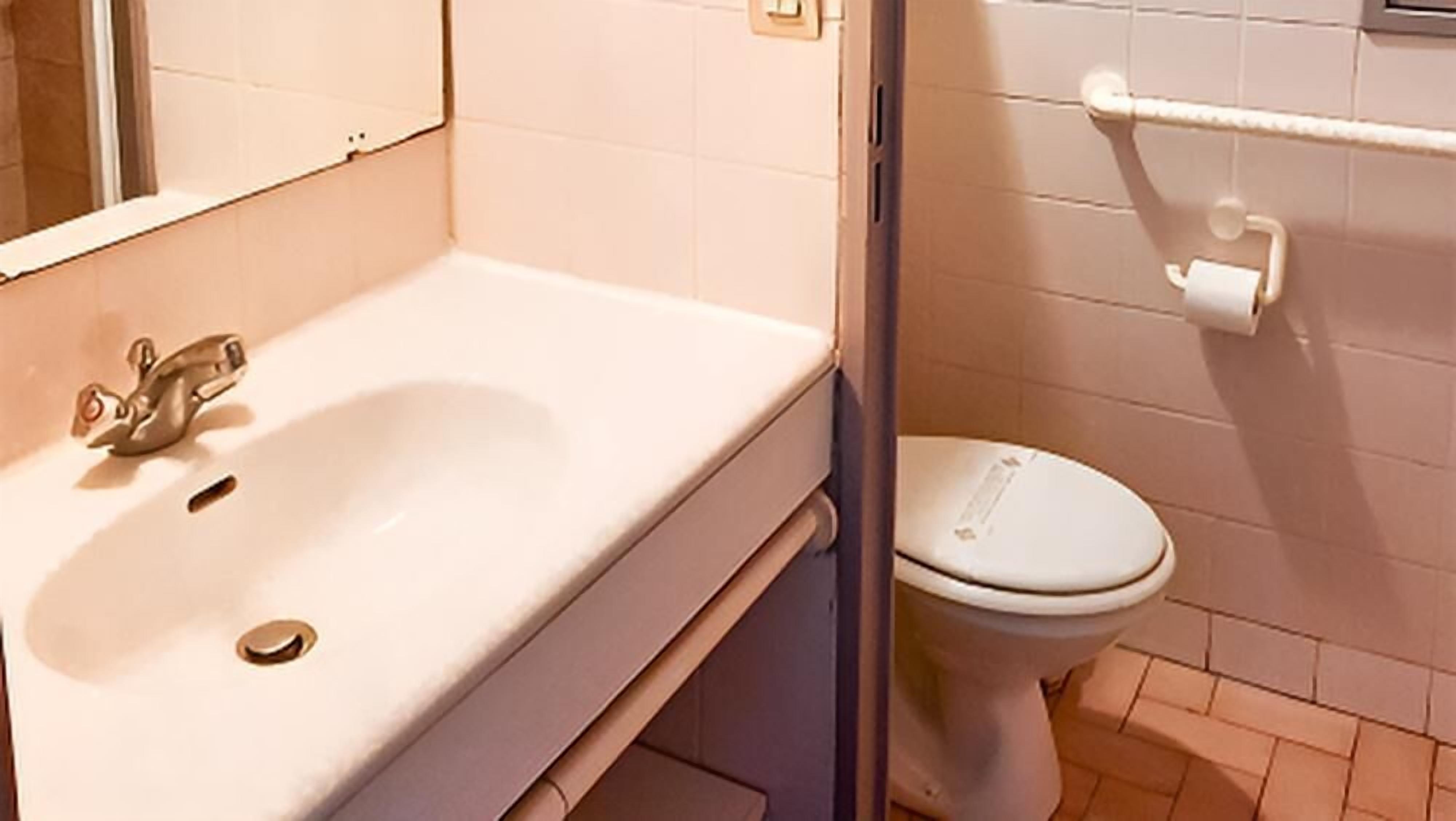 Un baño con lavamanos, espejo e inodoro.