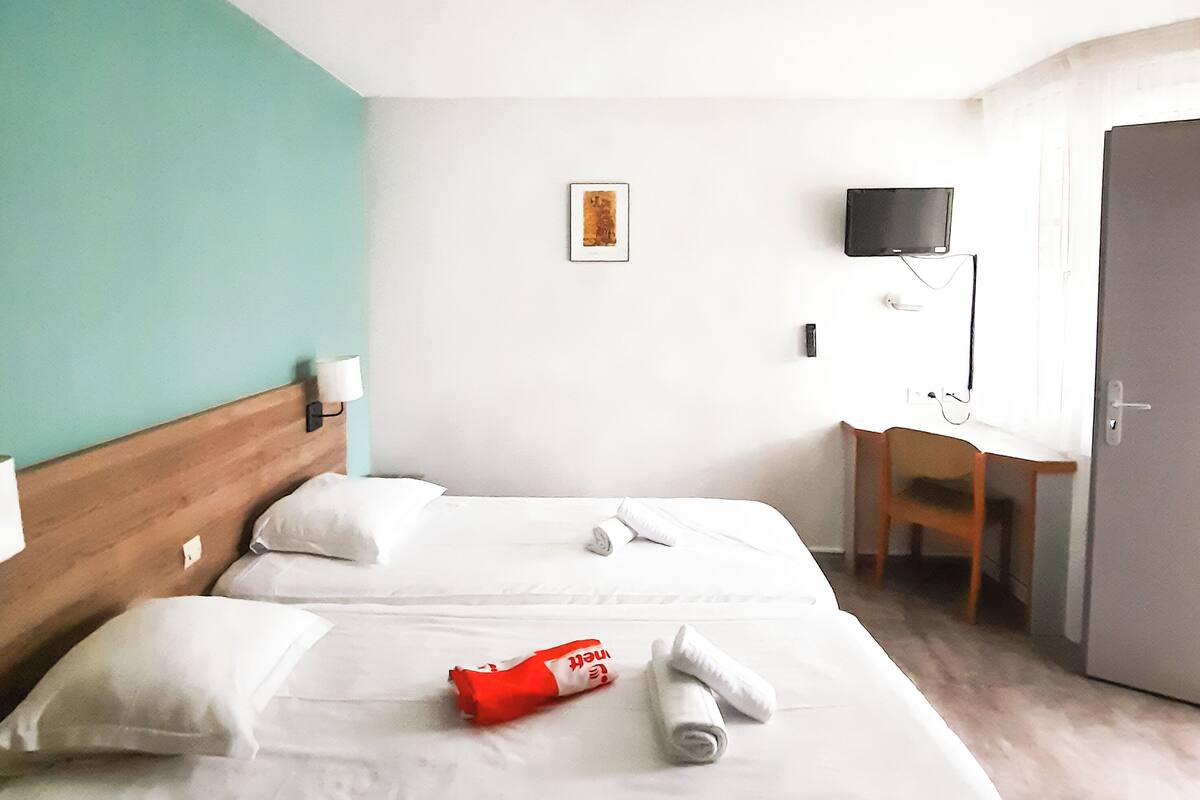 A hotel room with a bed, a desk, a television, and a door.