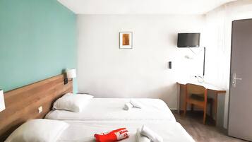A hotel room with a bed, a desk, a television, and a door.