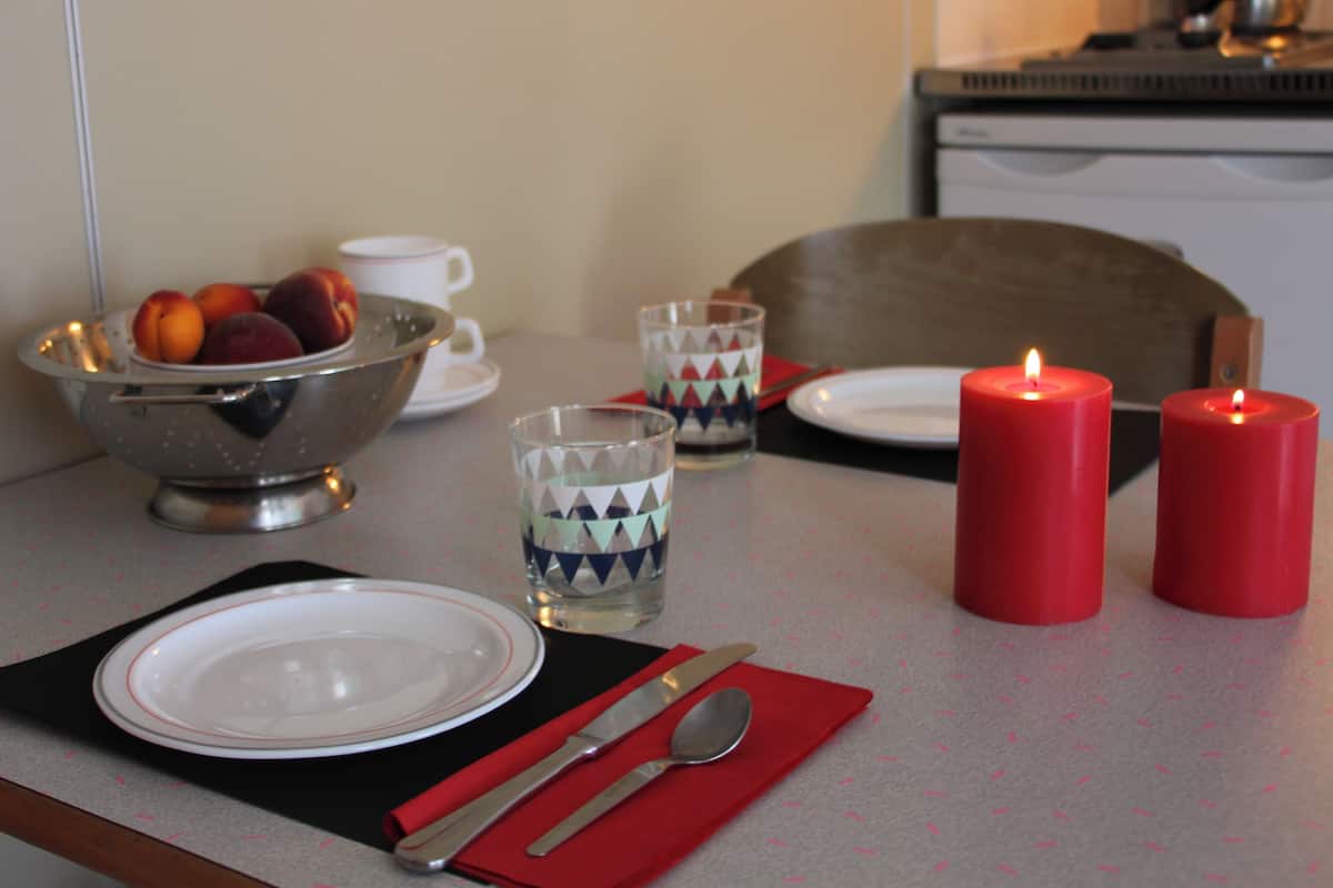 A dining table set with plates, cutlery, a bowl of fruit, glasses, and candles.
