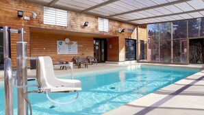 A swimming pool with a lifeguard chair, lounge chairs, and a wooden wall with windows and a sign. - VVF Plaine d'Alsace Obernai Strasbourg (Obernai)