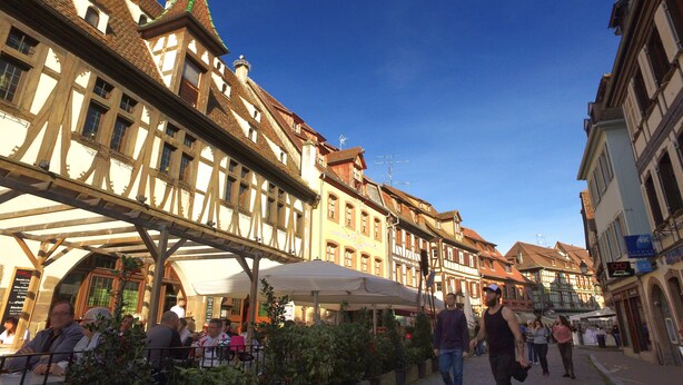 A street with traditional half-timbered buildings, outdoor seating, and a clear blue sky. - VVF Plaine d'Alsace Obernai Strasbourg (Obernai)