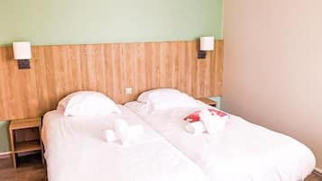 Een tweepersoonsbed met witte beddengoed in een kamer met groene muren en een houten hoofdeinde.