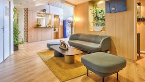 A modern hotel lobby with a sofa, coffee table, and potted plants.