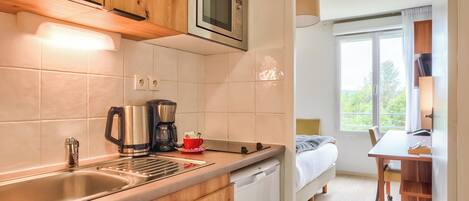 Une cuisine moderne avec des meubles en bois, un évier en acier inoxydable, une machine à café et un four à micro-ondes.