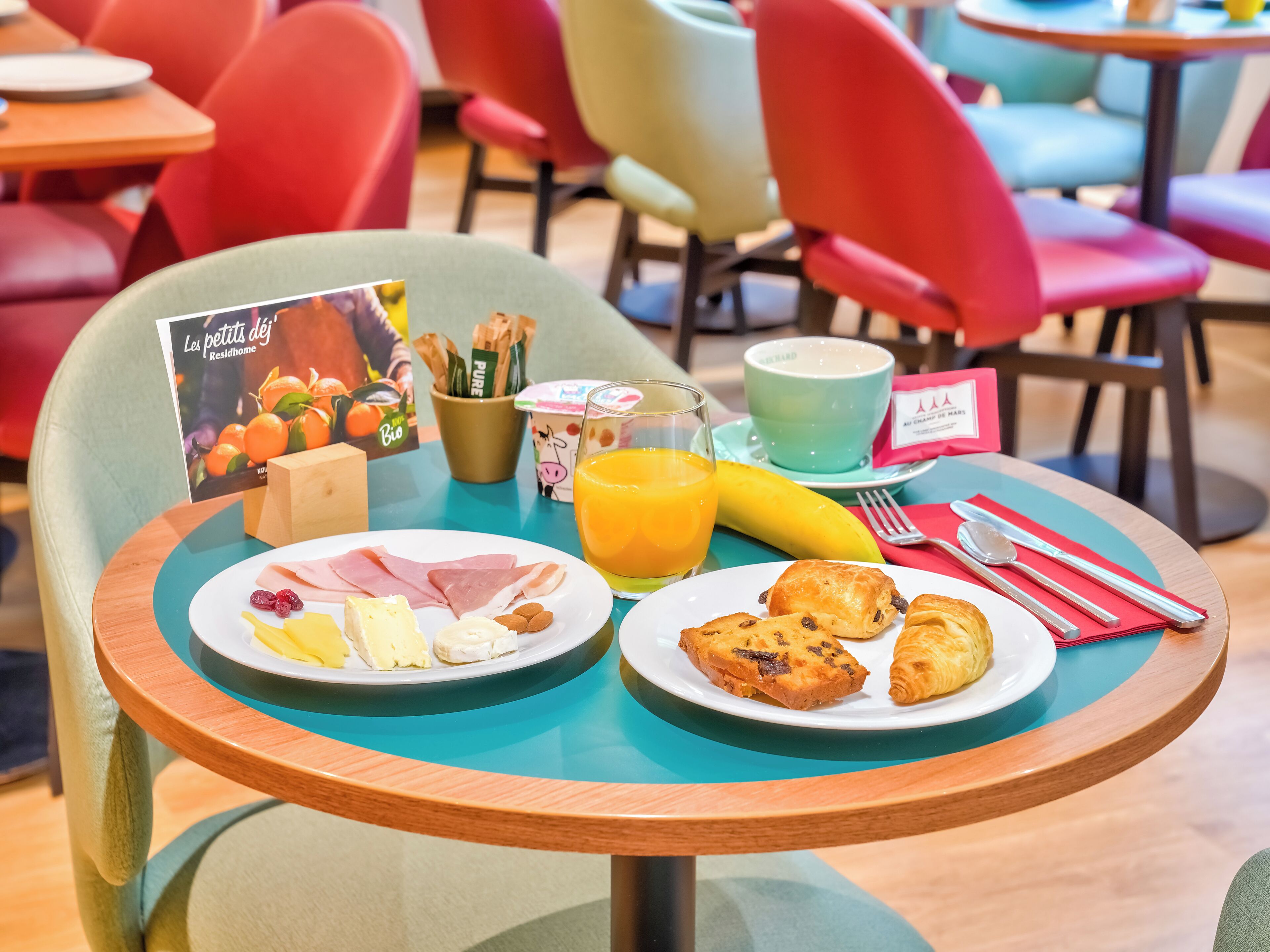 A breakfast table with plates of food, a coffee cup, and a menu.