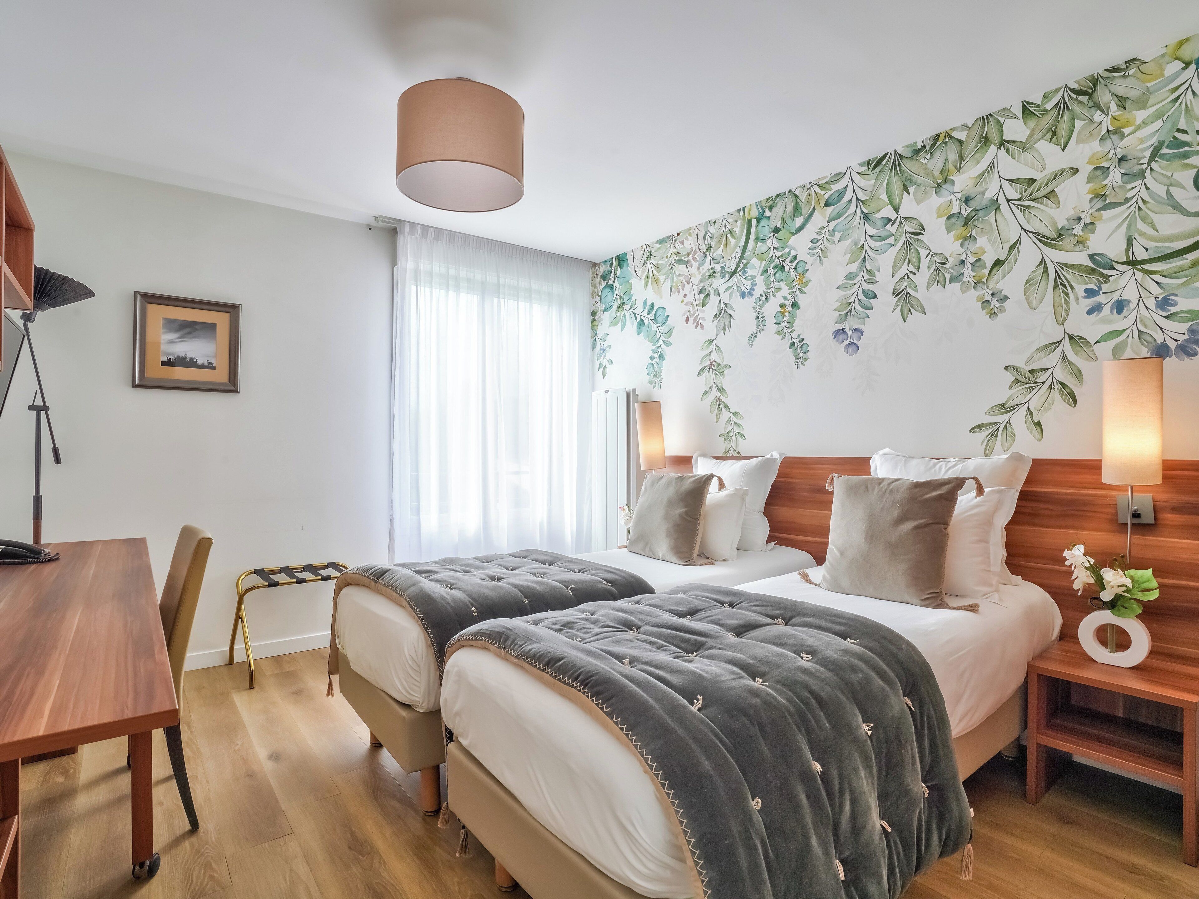 A hotel room with a bed, bedside tables, a desk, and a chair.