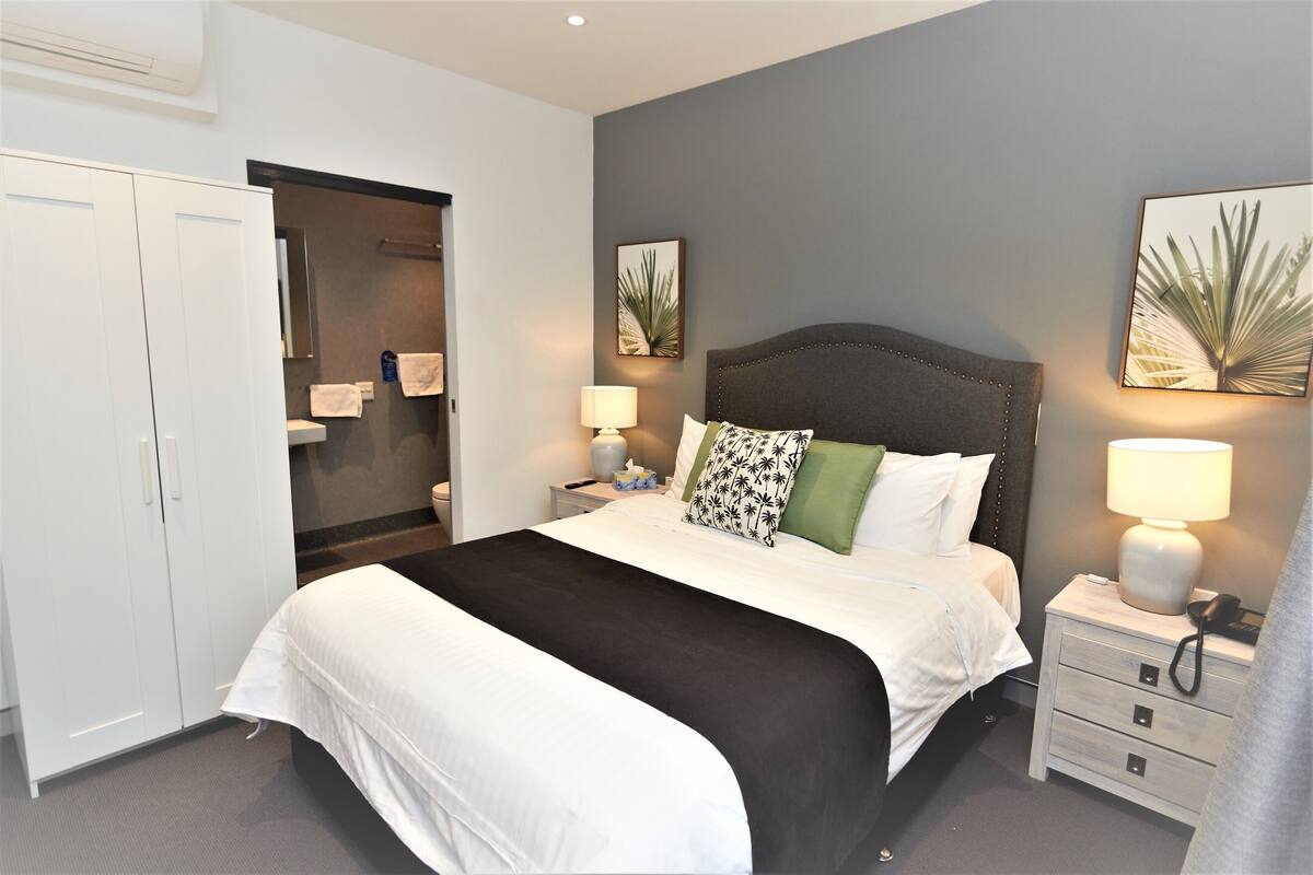 A bedroom with a bed, bedside tables, a wardrobe, and a mirror.