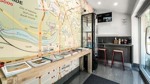Un mostrador de recepción con un mapa de Adelaide, taburetes de bar, una pantalla de televisión y un refrigerador.