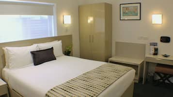 A hotel room with a bed, a desk, a wardrobe, and a dining area.