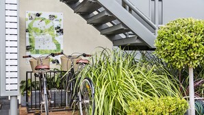 Una bicicleta estacionada junto a un mapa en la pared, una escalera y varias plantas.