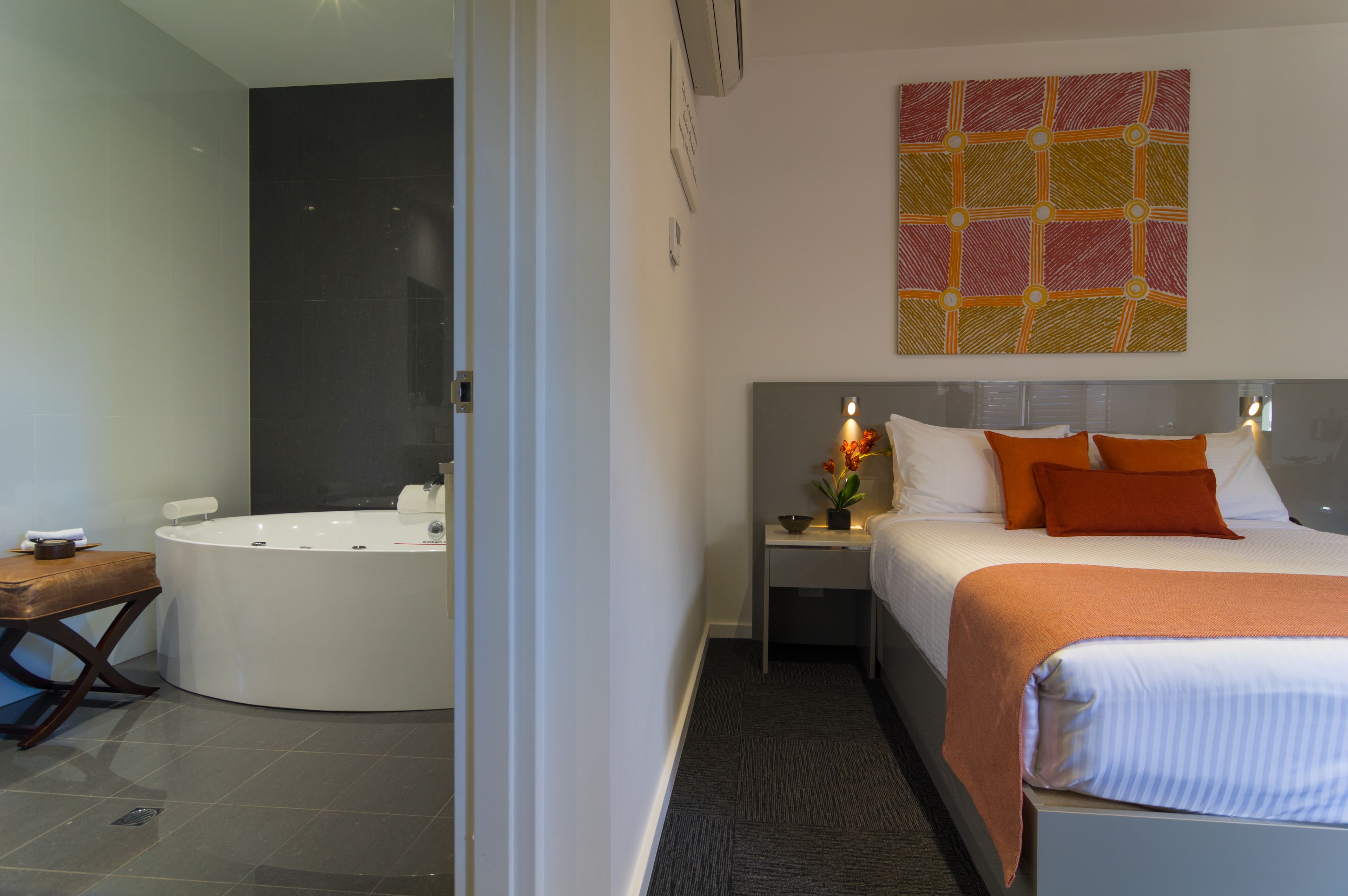 Una habitación de hotel moderna con una cama grande, un baño separado con bañera y una pequeña mesa con una silla.