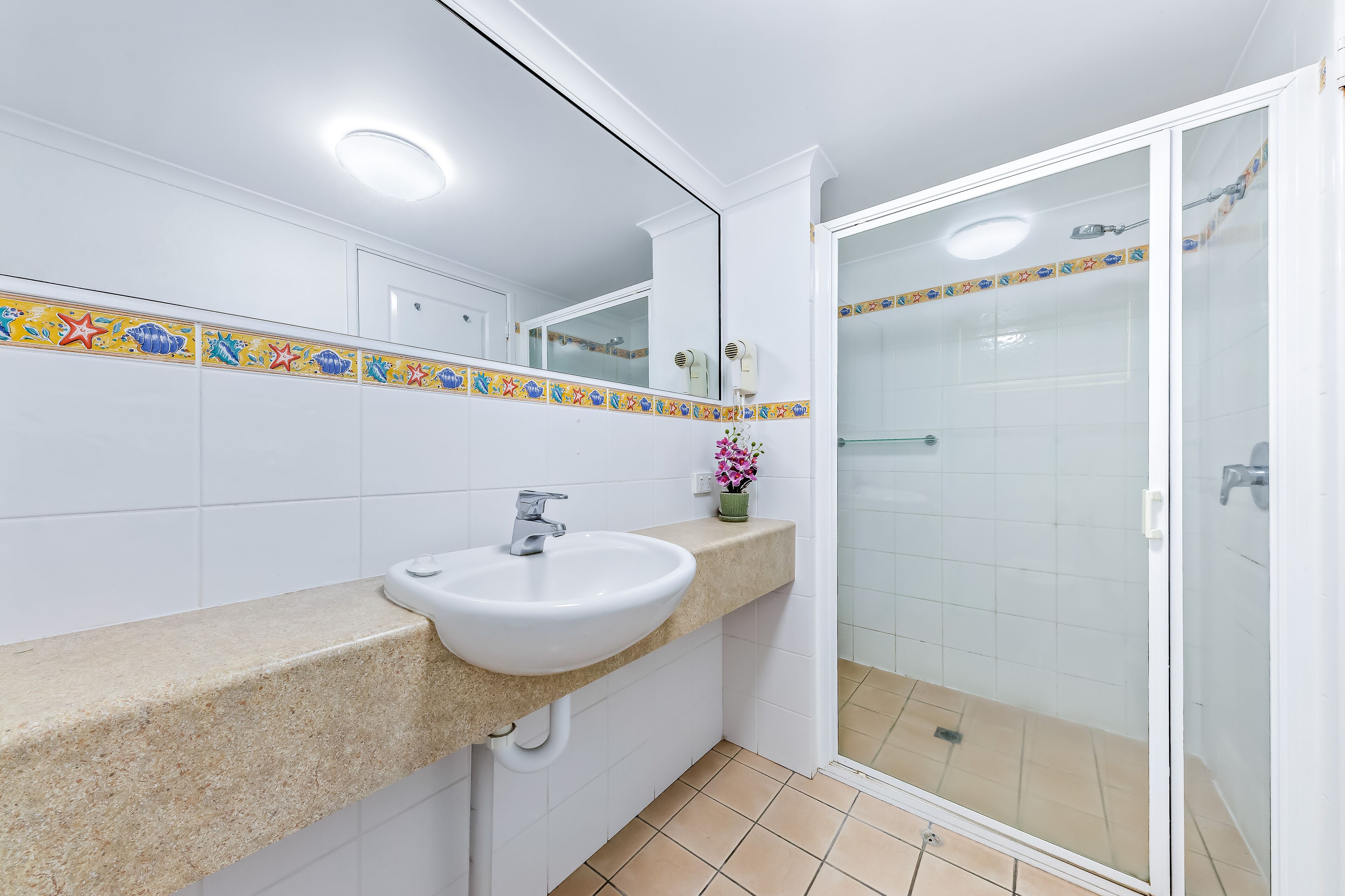 A bathroom with a white sink, a mirror, and a shower with a glass door.