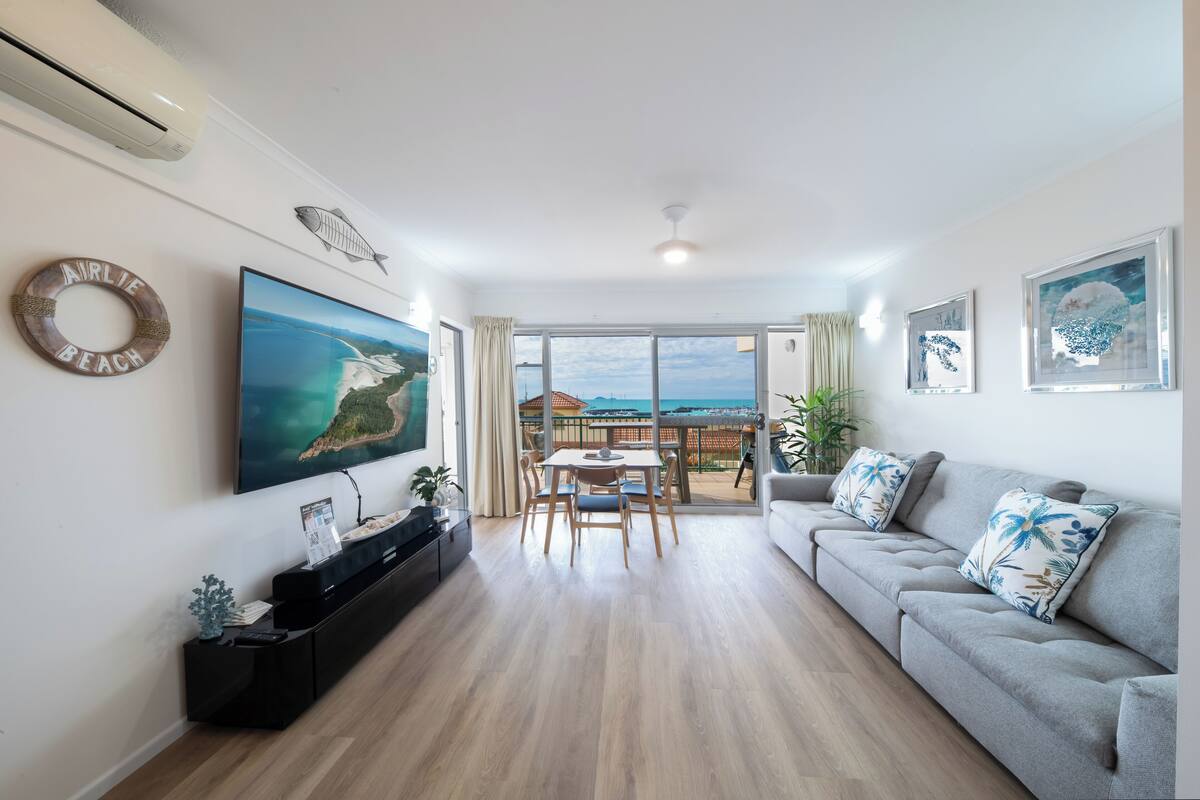 A living room with a flat-screen TV, a sofa, and a dining table.