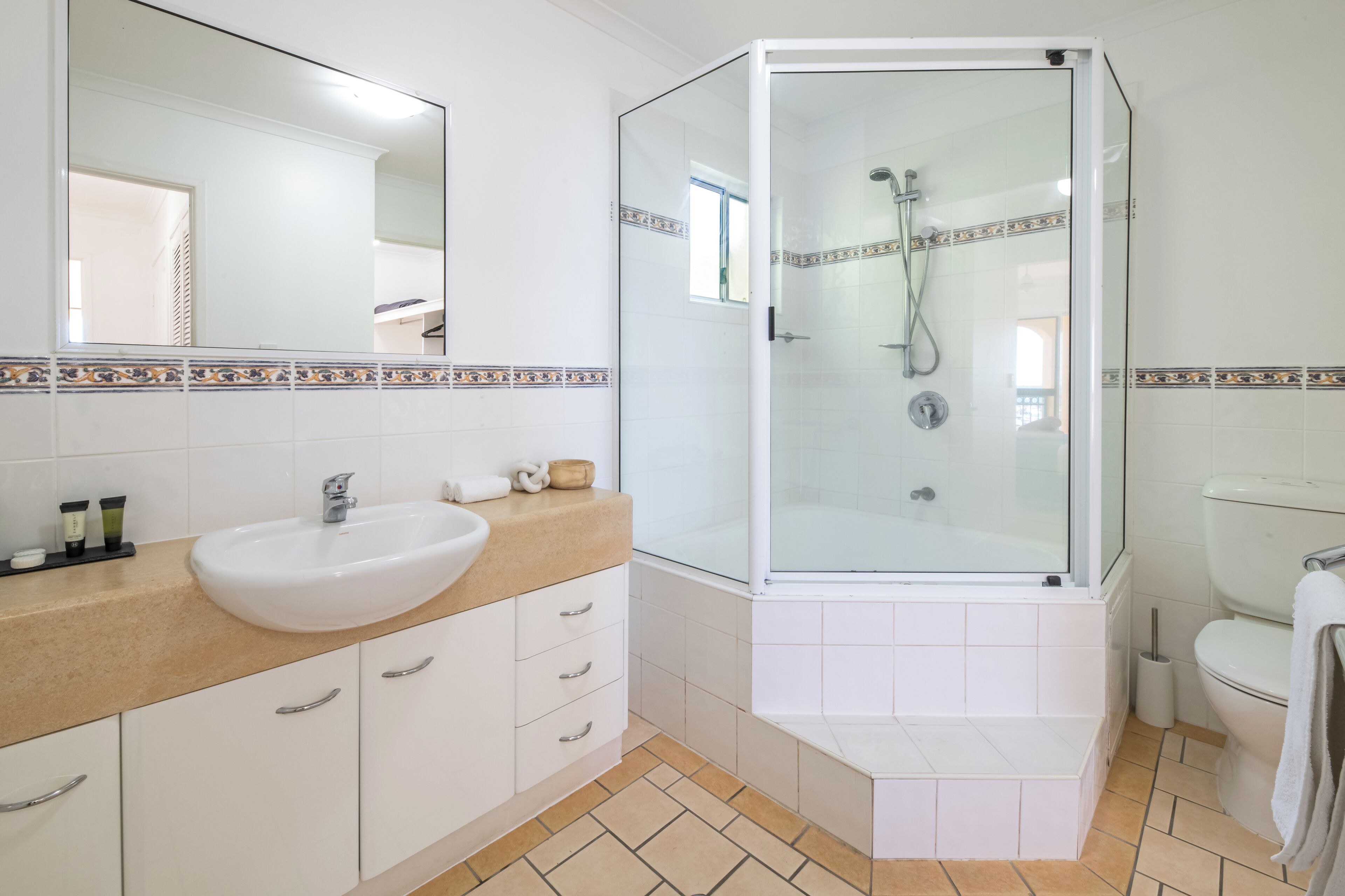 A bathroom with a white sink, a glass-enclosed shower, and a toilet.