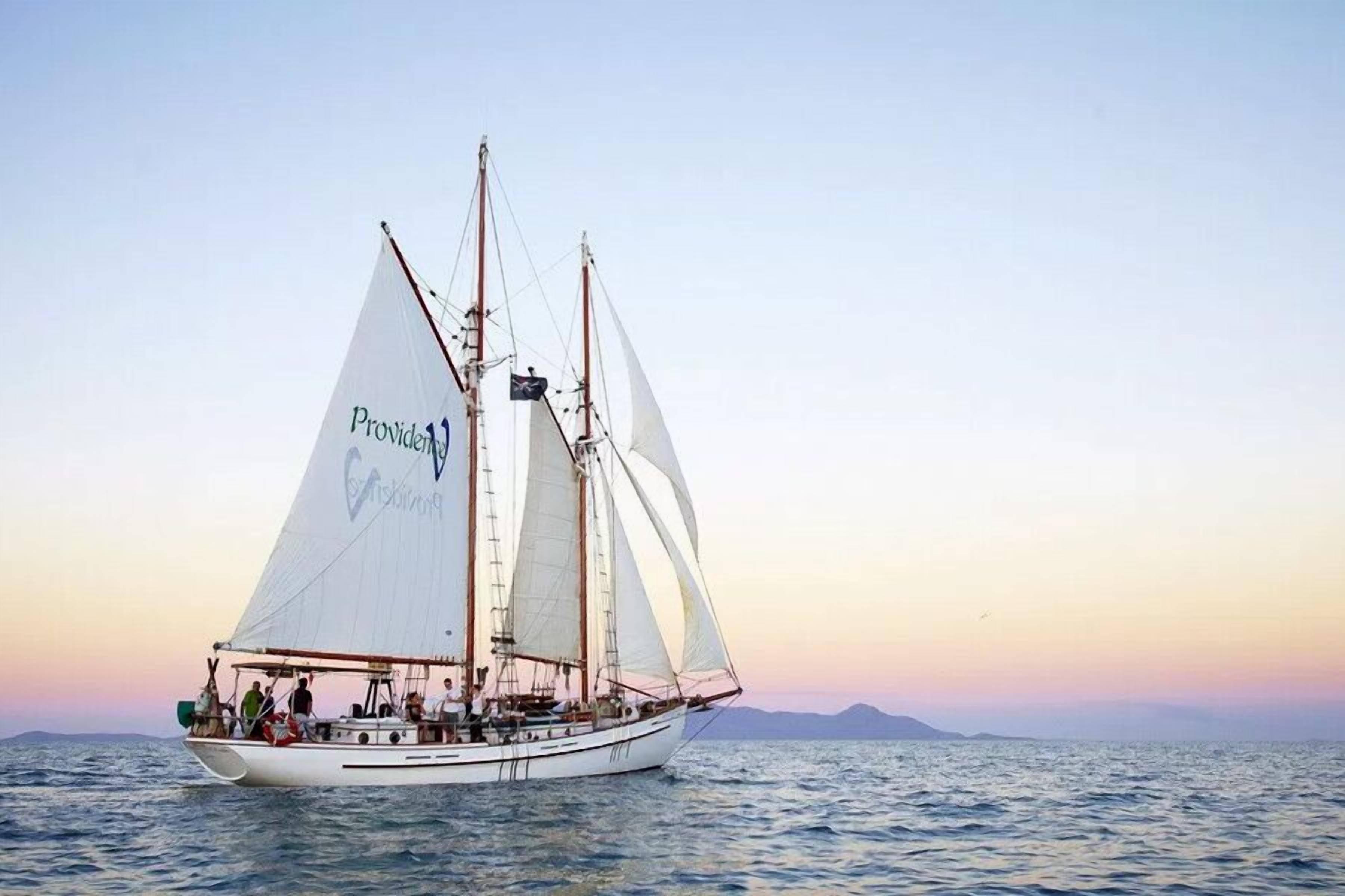 Un velero con el nombre "Providence" en sus velas, navegando sobre aguas tranquilas.