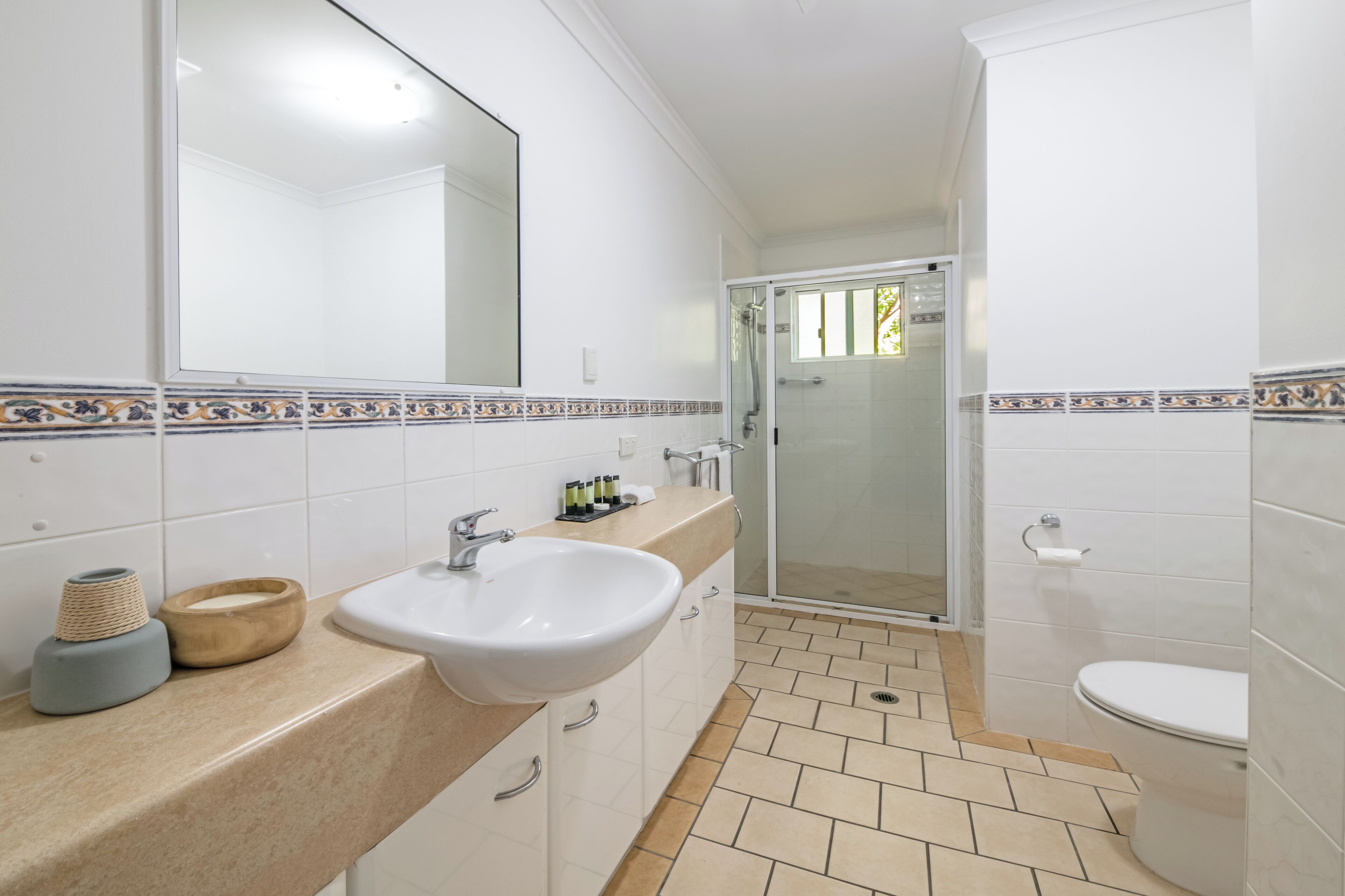 A bathroom with a sink, mirror, shower, and toilet.