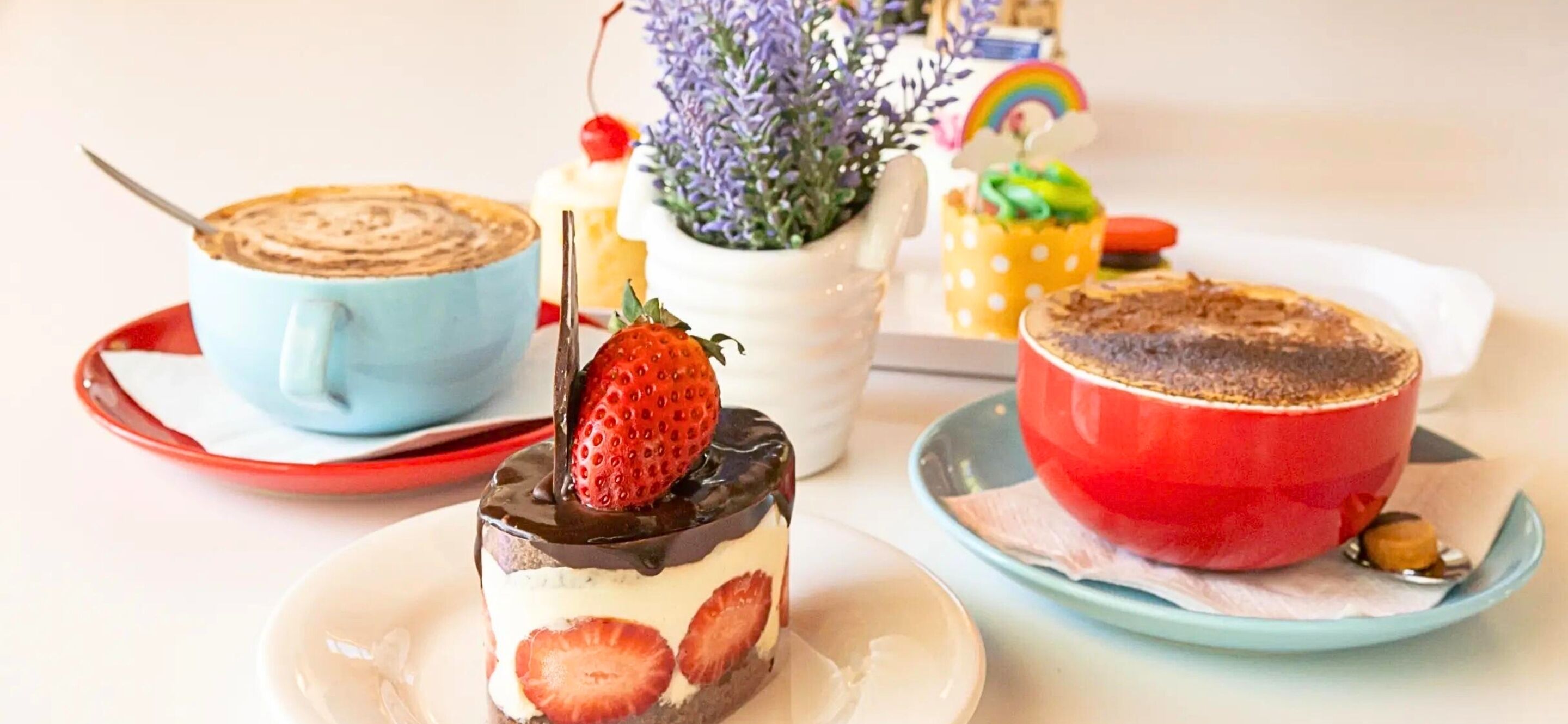 A dessert table with various cakes and a coffee cup.