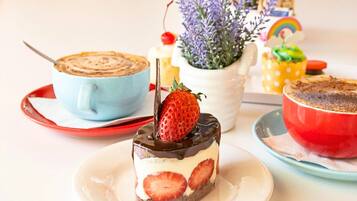 A dessert table with various cakes and a coffee cup.