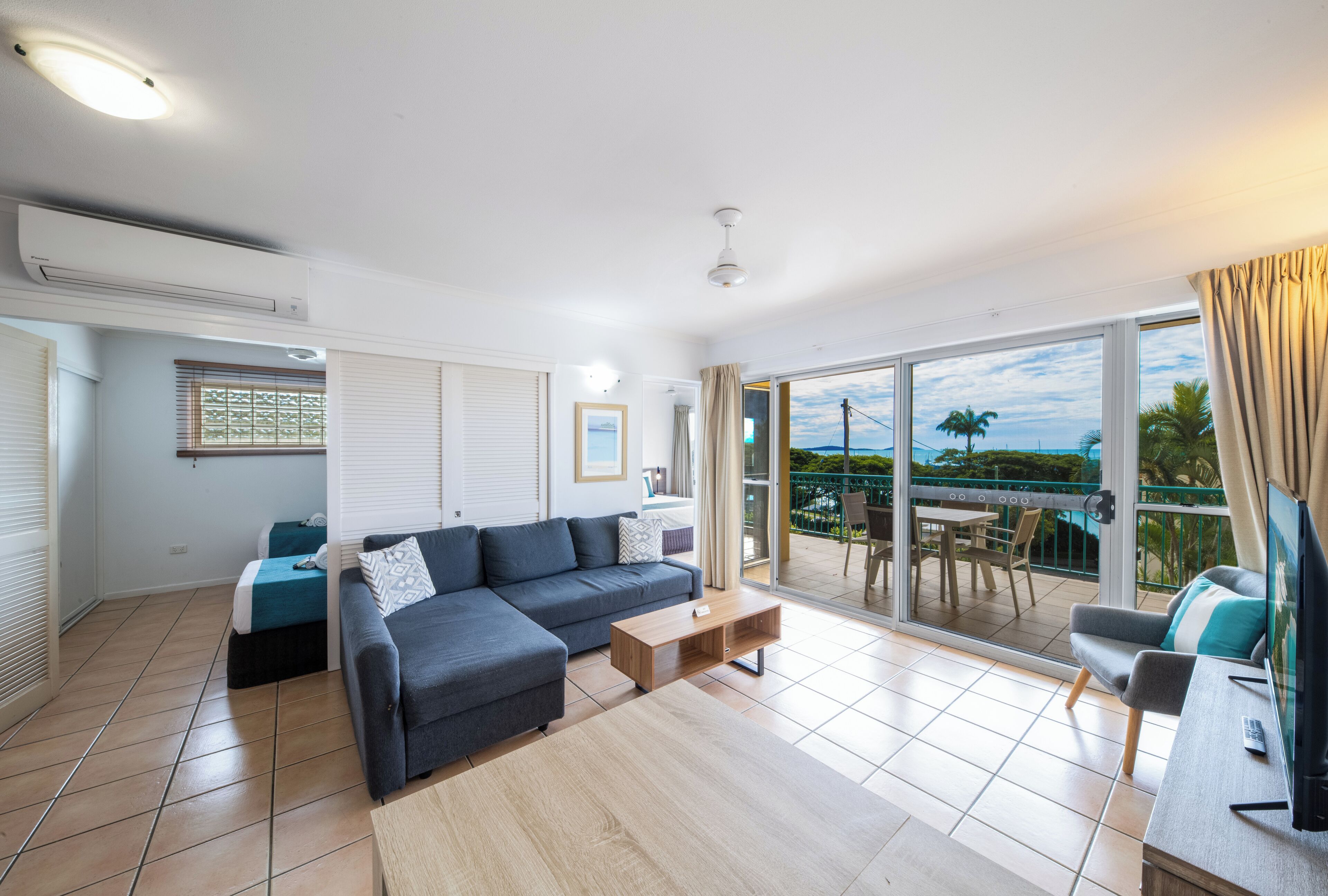 A modern living room with a sofa, coffee table, and a balcony with a table and chairs.