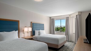 A hotel room with two beds, a TV, a desk, and a window with a view of the outdoors. - Homewood Suites West Palm Beach (West Palm Beach)