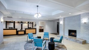 A modern lobby with a reception desk, seating area, and a fireplace. - Homewood Suites West Palm Beach (West Palm Beach)