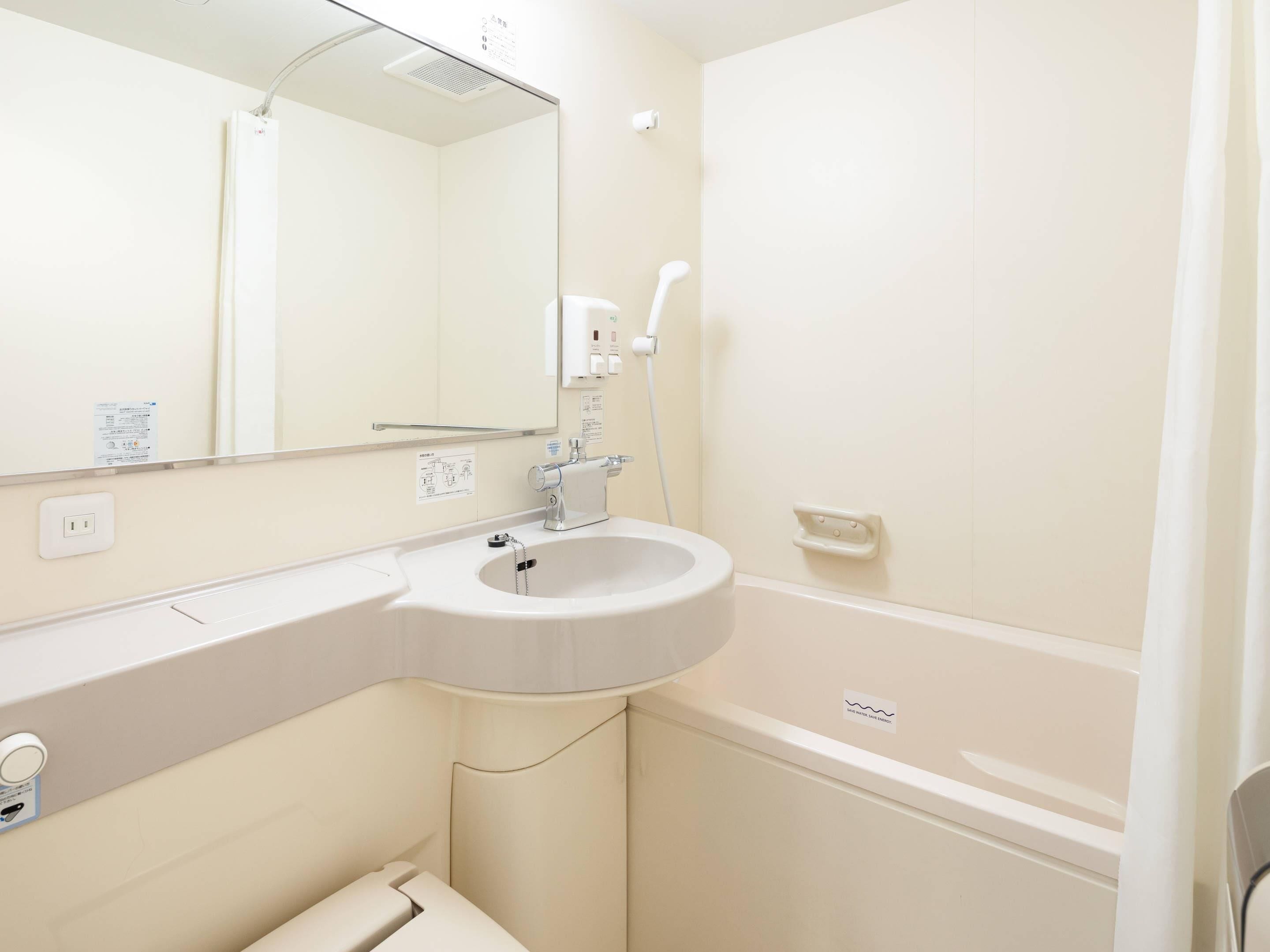 A bathroom with a white sink, mirror, and bathtub.