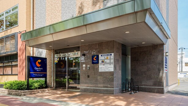 Entrada de un hotel con un corredor cubierto, un letrero del Comfort Hotel y un mapa que indica la ubicación del hotel.