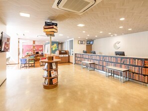 A library with a wooden reception desk, bookshelves, and a signpost indicating directions to Florida, Tokyo, and Rinkoku. - Comfort Hotel Maebashi (Maebashi)