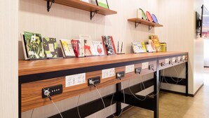 Una recepción con detalles de madera, varias estaciones de carga y estantes con libros y objetos decorativos.