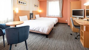 Habitación de hotel con cama, dos mesitas de noche, un escritorio con una computadora, una silla y una pequeña mesa.