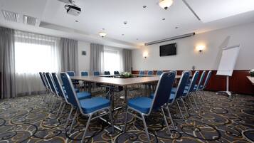 A conference room with a long table, blue chairs, a projector, and a whiteboard.