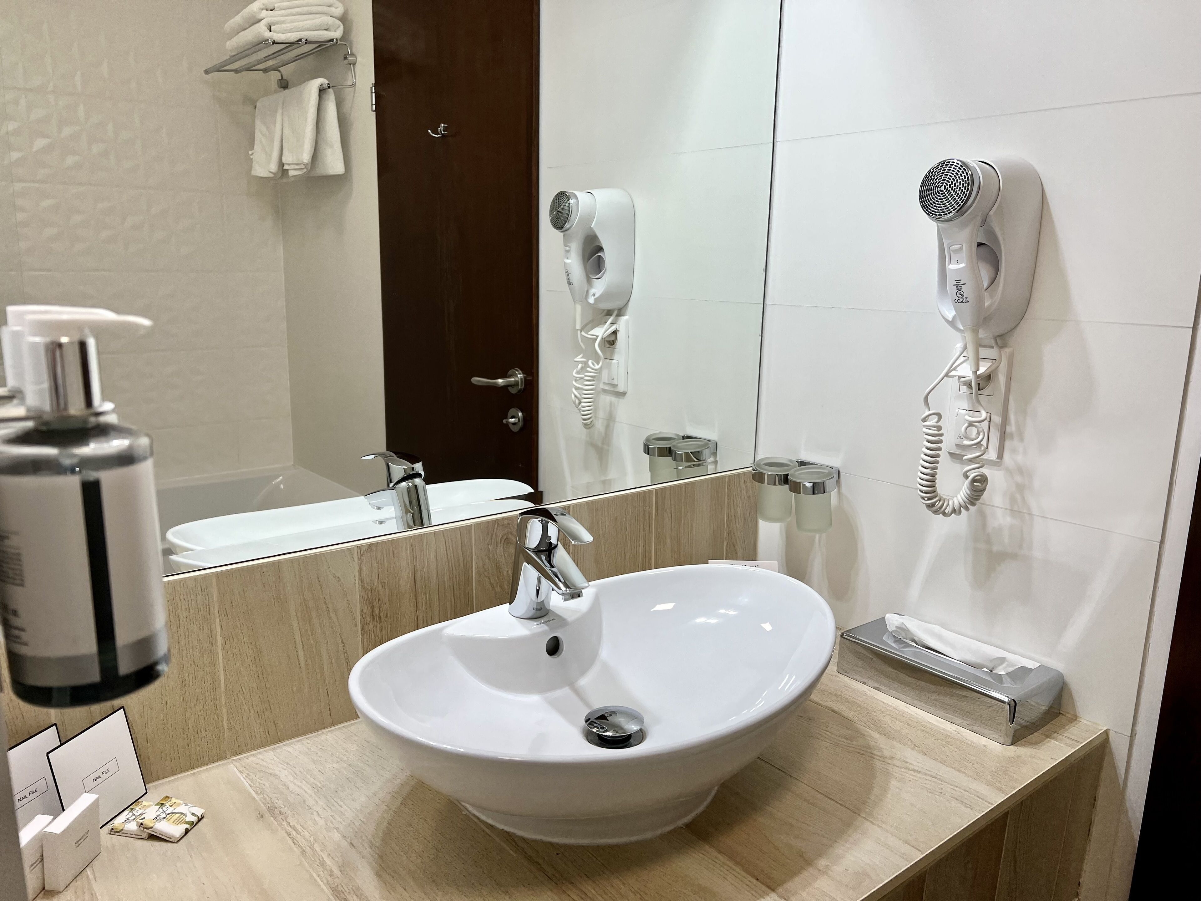 A bathroom with a white sink, a mirror, a hairdryer, and a telephone.