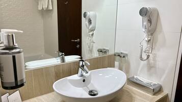 A bathroom with a white sink, a mirror, a hairdryer, and a telephone.