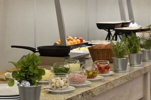 Montaje de bufé con diferentes alimentos y una estación de cocina.