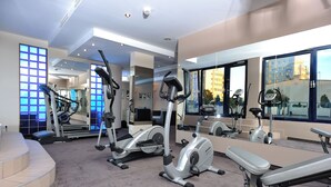 Un gimnasio moderno con diversas máquinas de cardio, un banco y una escalera que lleva a un nivel superior.