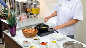 Montaje de bufé con distintos alimentos y una persona cocinando.