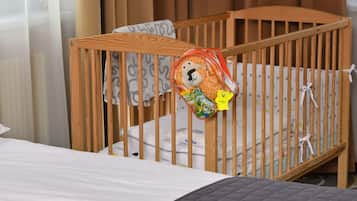 A cozy space for little ones, featuring a crib with a comfortable mattress and a bed in the background.