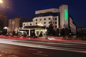 A City Hotel with a modern facade, multiple floors, and a prominent green sign. - City Hotel (Bydgoszcz)