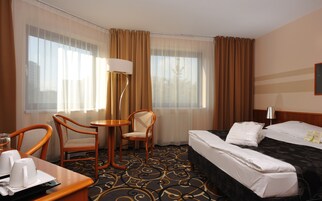 Una habitación de hotel con cama, dos sillas, una mesita y una lámpara.