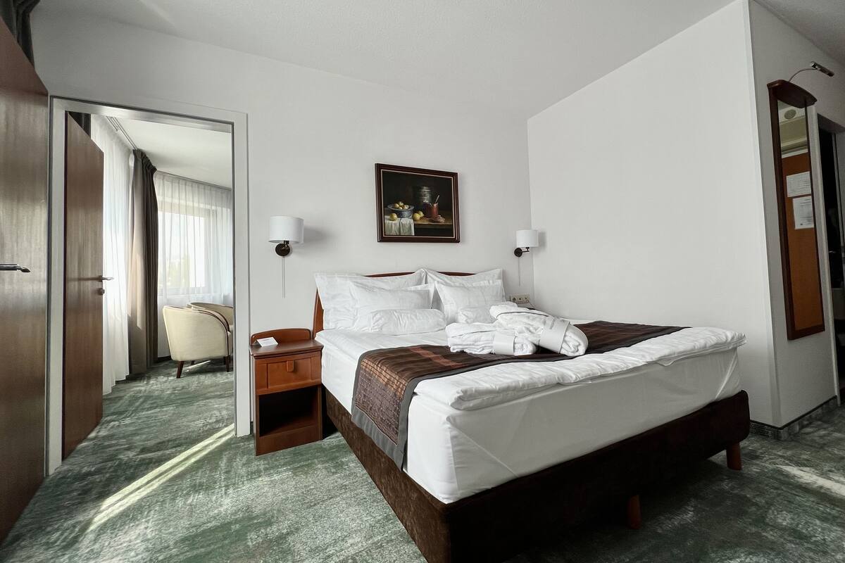 Una habitación de hotel con una cama grande, un escritorio, una silla y un cuadro en la pared.