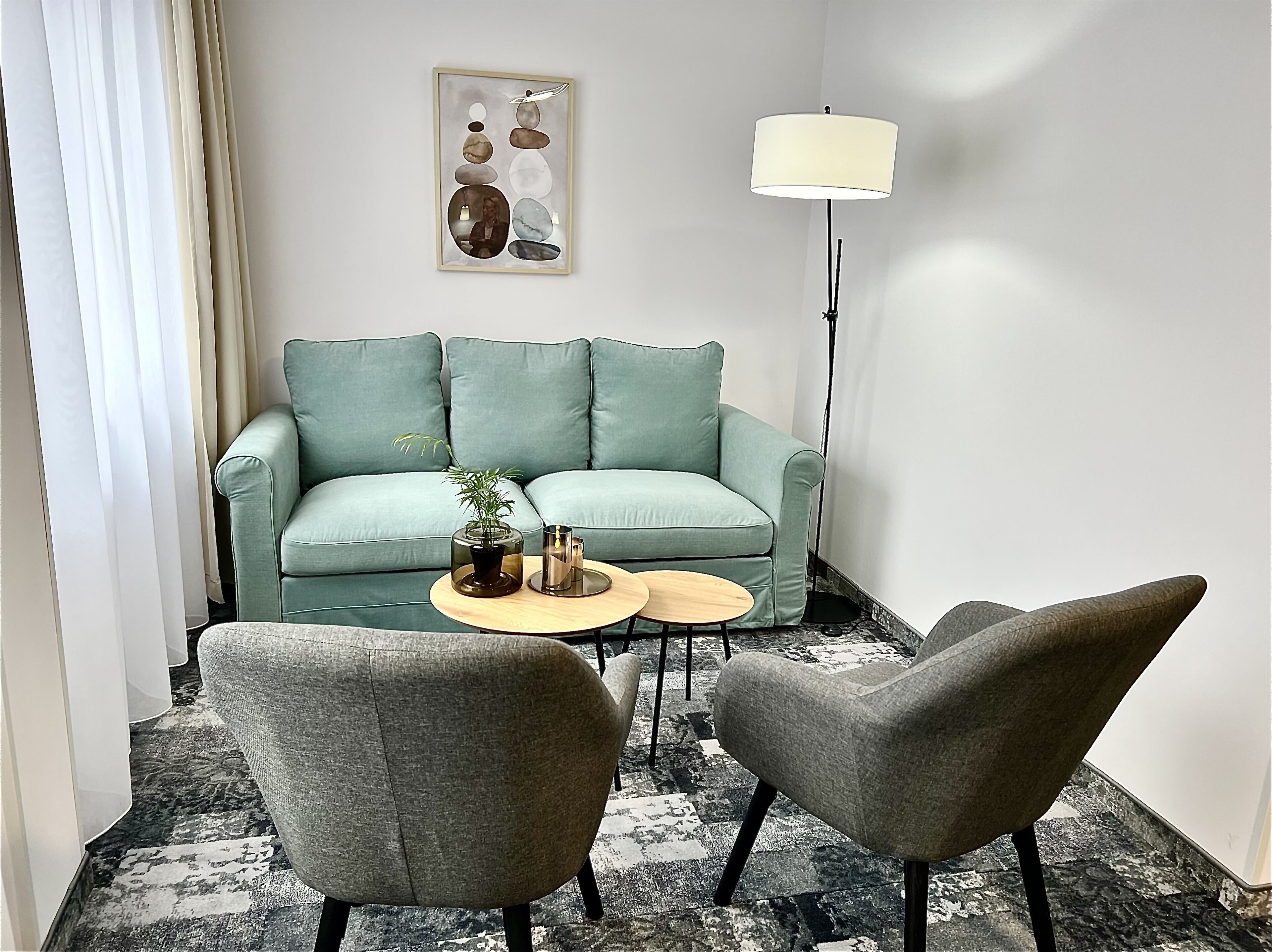 Una sala de estar moderna con un sofá azul aguamarina, dos sillones, una mesita de centro, una lámpara de pie y un elemento decorativo en la pared.